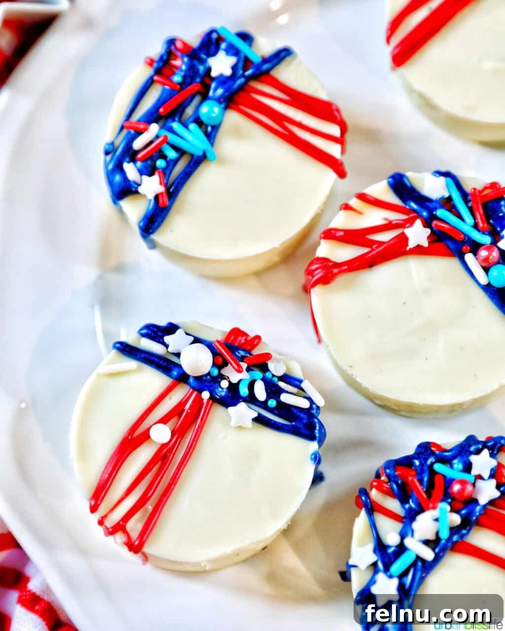 Fourth of July-Themed Oreo Delights 14 Close-up of a white chocolate covered Oreo cookie with red and blue frosting and sprinkle decorations.