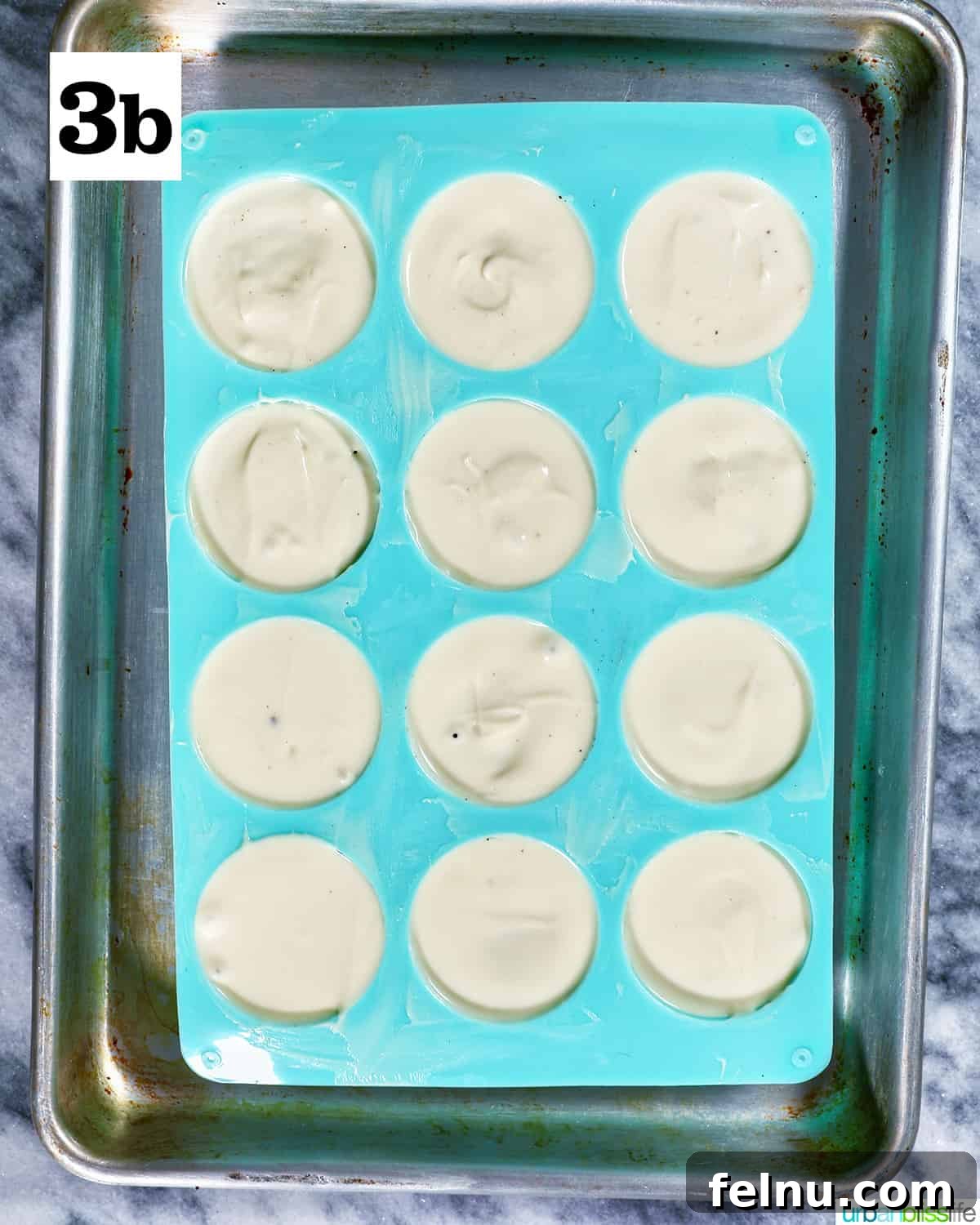 Fourth of July-Themed Oreo Delights 8 White chocolate covered Oreo cookies in a blue chocolate candy mold on a baking sheet.