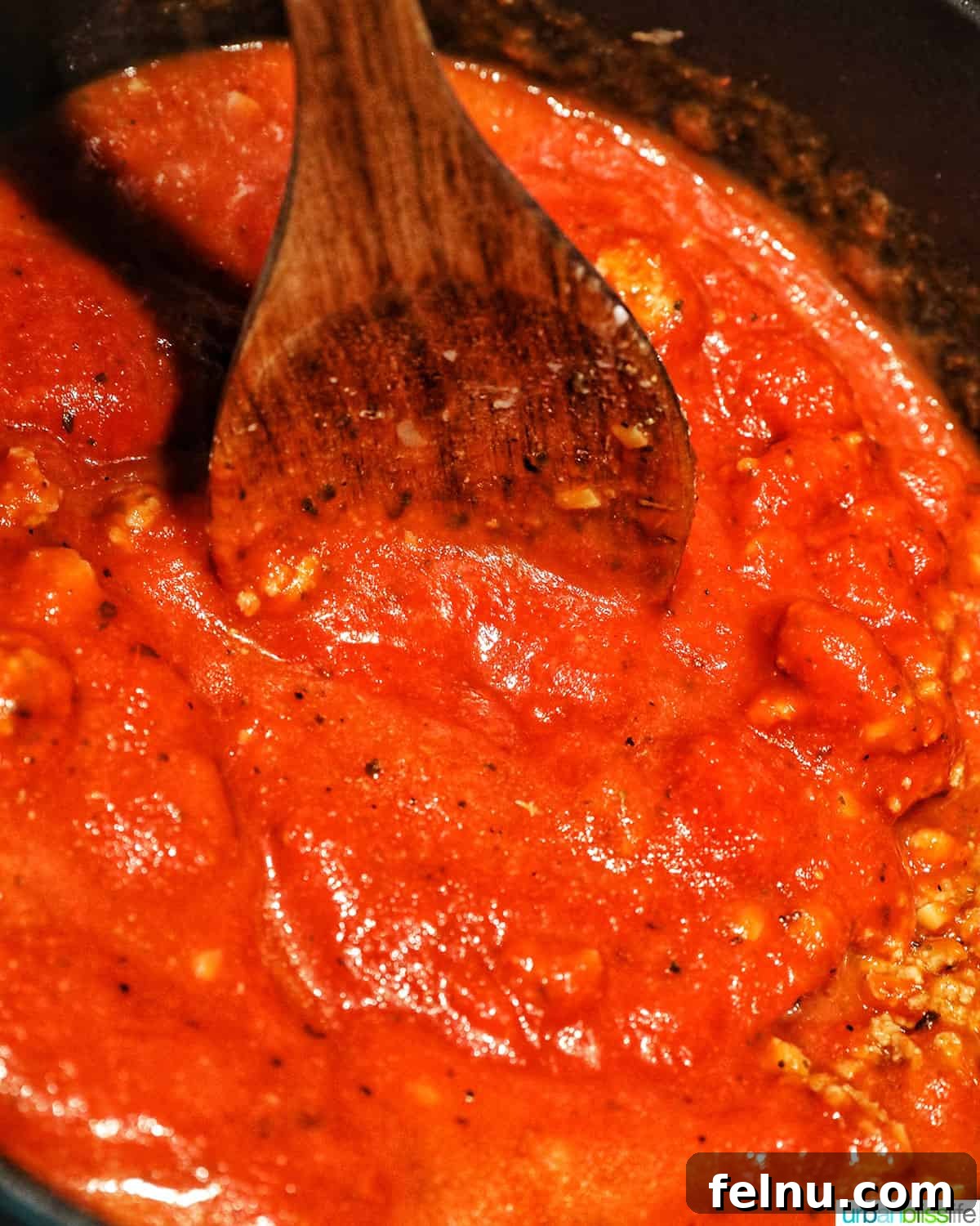 Creamy Vegan Lasagna 15 wooden spoon stirring marinara sauce in a dutch oven.