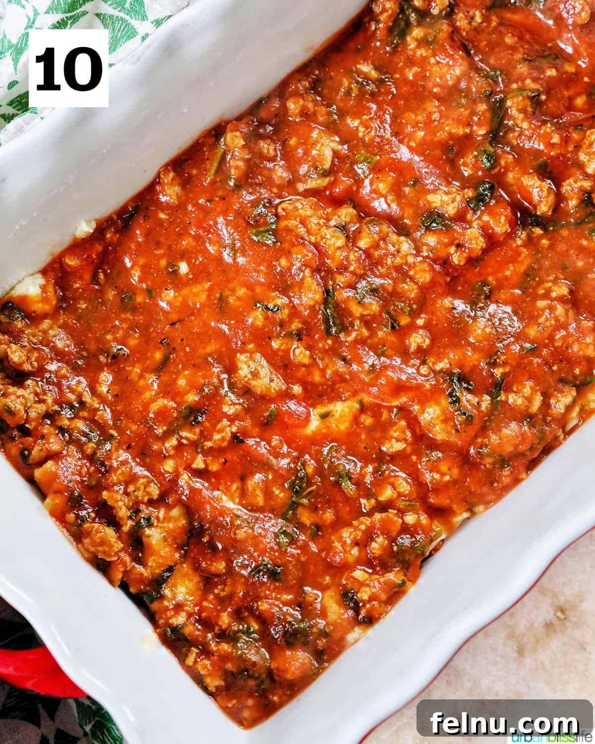Creamy Vegan Lasagna 21 ground turkey marinara sauce in a white baking dish with red handles.