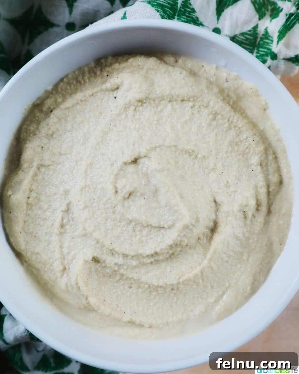 Creamy Vegan Cashew Cheese 3 A pristine white bowl filled with creamy Vegan Cashew Cheese, resting on a charming green and white patterned napkin.