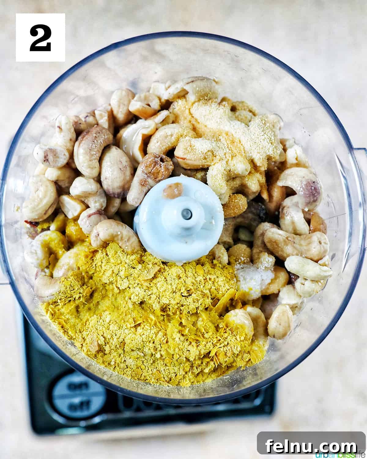 Creamy Vegan Cashew Cheese 6 All the prepped ingredients for Vegan Cashew Cheese, including soaked cashews, nutritional yeast, lemon juice, and garlic powder, placed inside a food processor bowl, ready for blending.