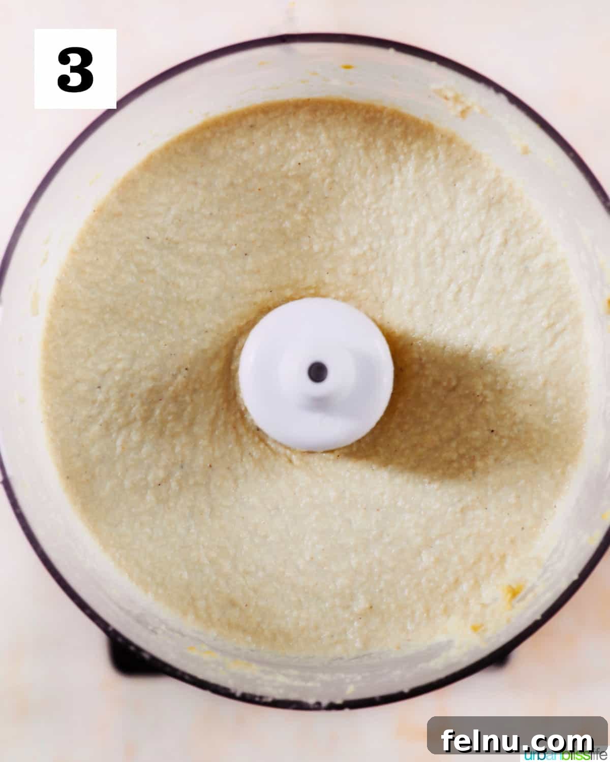 Creamy Vegan Cashew Cheese 7 The smooth and creamy texture of freshly blended Vegan Cashew Cheese inside a food processor, indicating a successful blend.