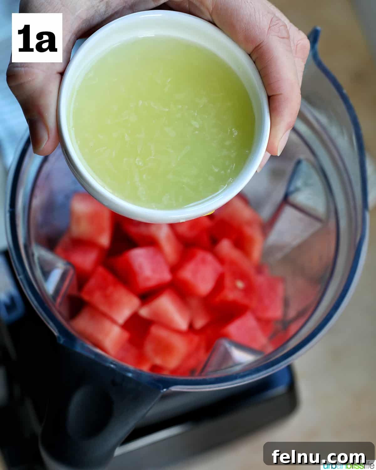 Watermelon Sunset Fizz 6 A hand pouring fresh lime juice from a small bowl into a blender filled with cubed watermelons, adding a tangy zest to the mimosa base.