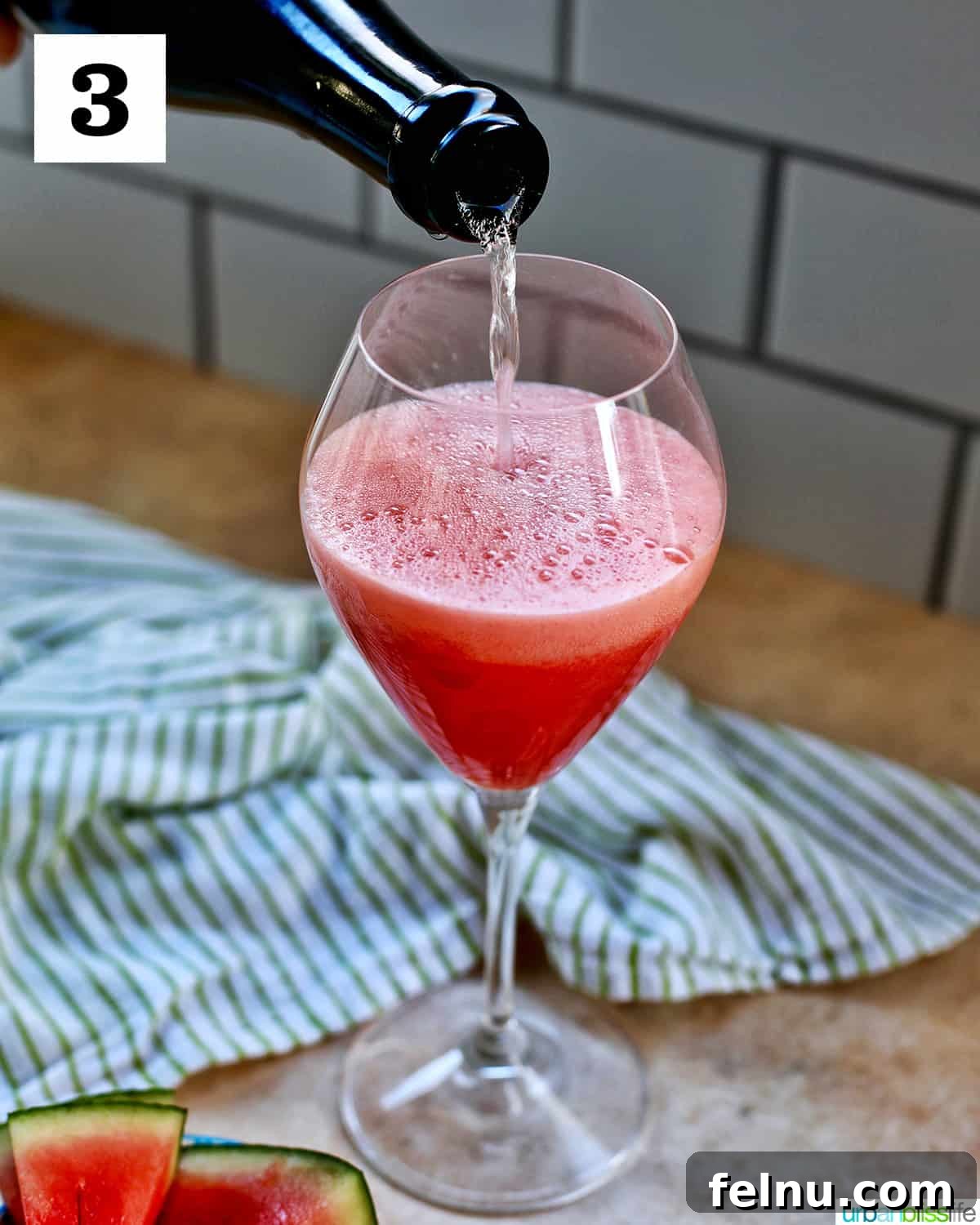 Watermelon Sunset Fizz 9 A close-up shot of sparkling Champagne being poured into a glass already filled halfway with the vibrant watermelon puree, creating a beautiful layered Watermelon Mimosa.