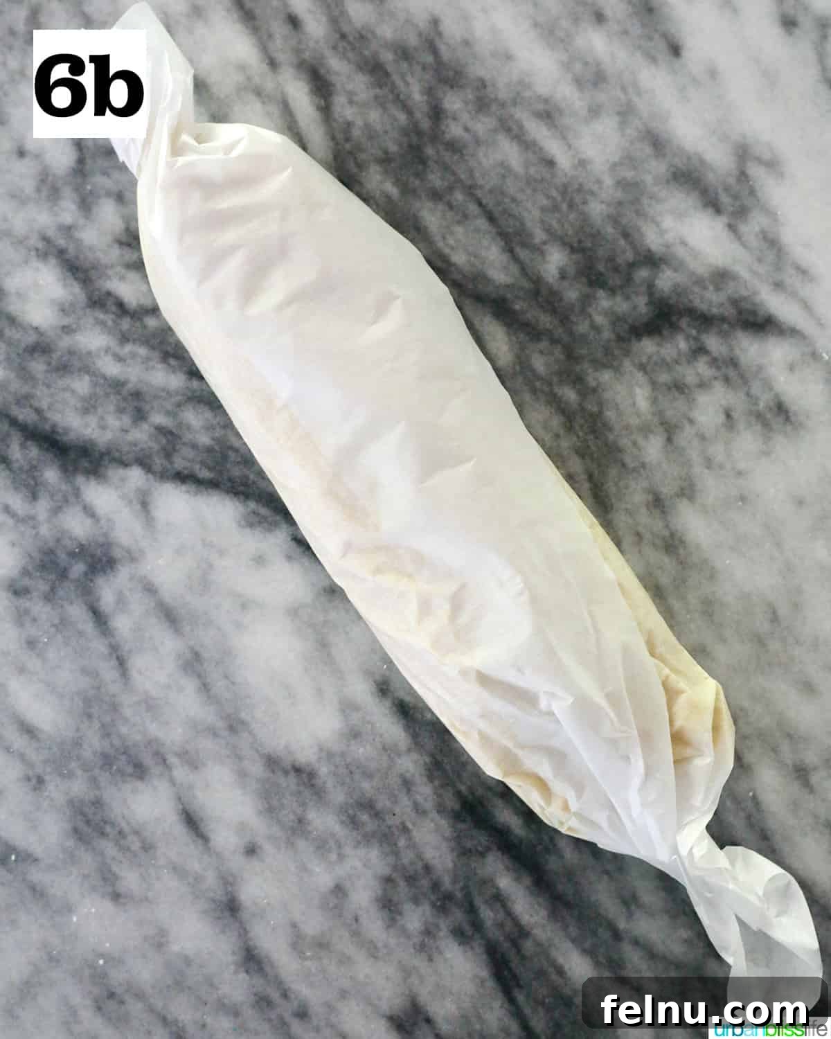 Tangy Key Lime Delights 15 A roll of key lime cookie dough neatly wrapped in parchment paper, resting on a marble countertop, prepared for chilling.