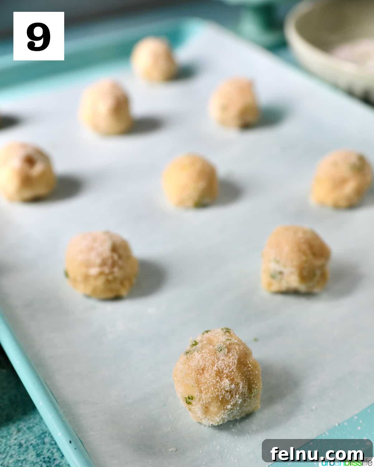 Tangy Key Lime Delights 18 Uniform key lime cookie dough balls, generously coated in sugar, neatly spaced on a parchment paper-lined baking sheet.