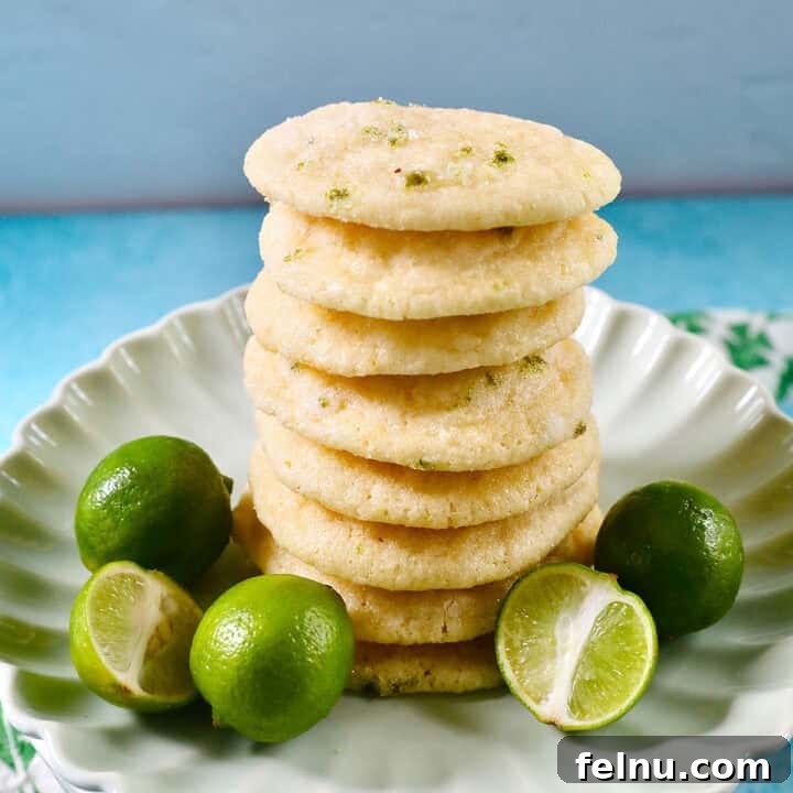 Tangy Key Lime Delights 21 A stack of perfectly baked key lime cookies on a plate, positioned next to several fresh key limes, ready for consumption.