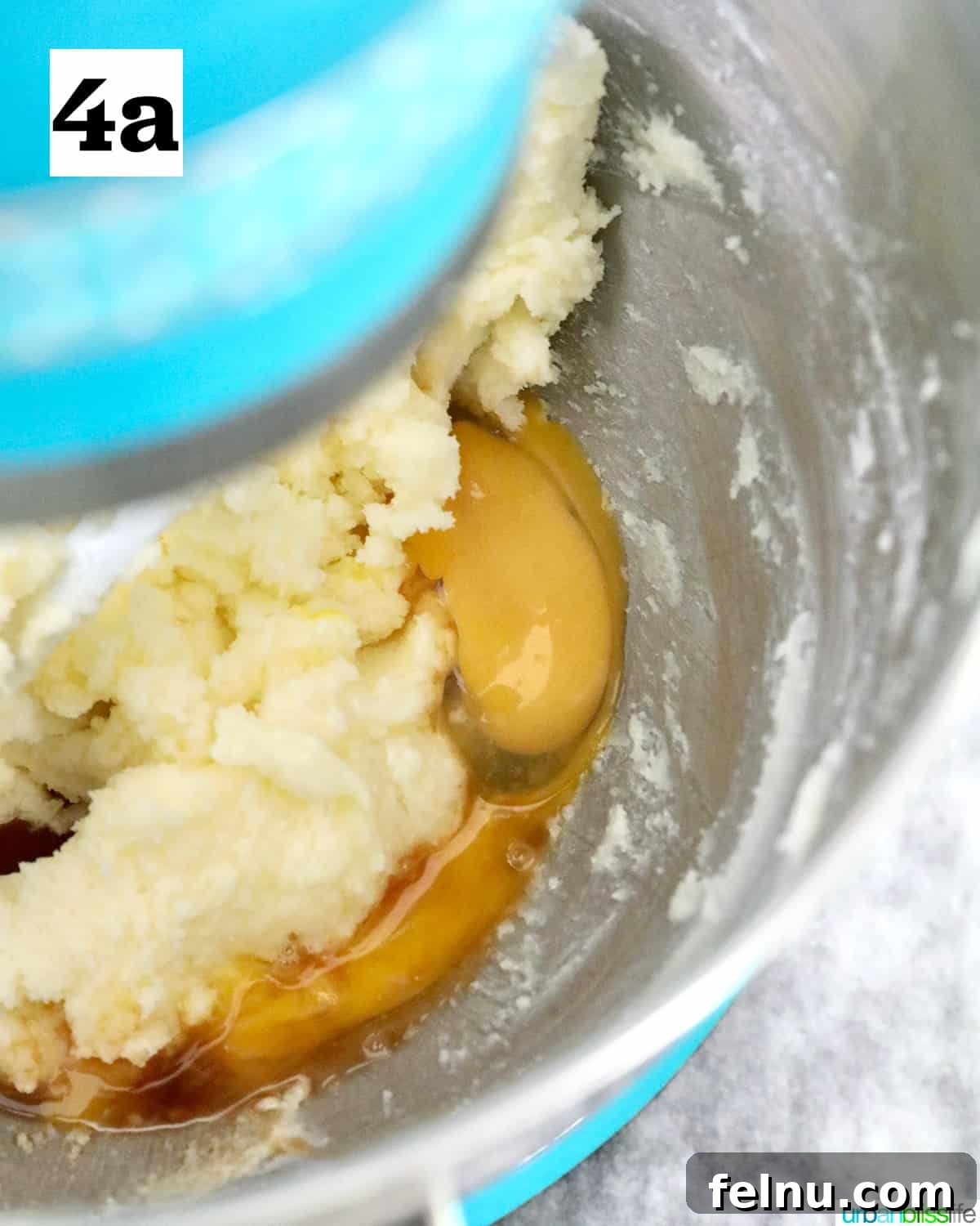 Tangy Key Lime Delights 10 A large egg being cracked and added into the creamy butter and sugar mixture in a stand mixer bowl, for key lime sugar cookies.