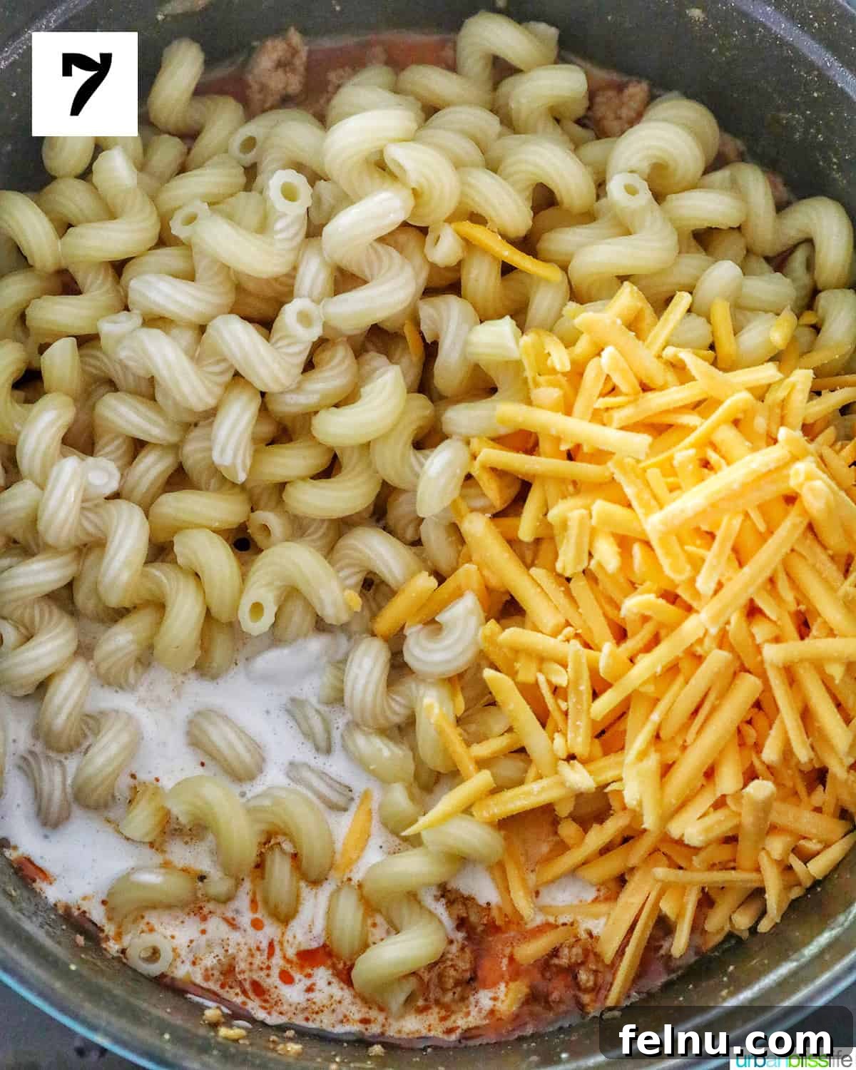 Creamy Dairy-Free Cheeseburger Mac Skillet 11 Dairy-free cheddar-style shreds and dairy-free heavy cream being stirred into the cooked pasta and sauce, creating a rich and creamy finish.