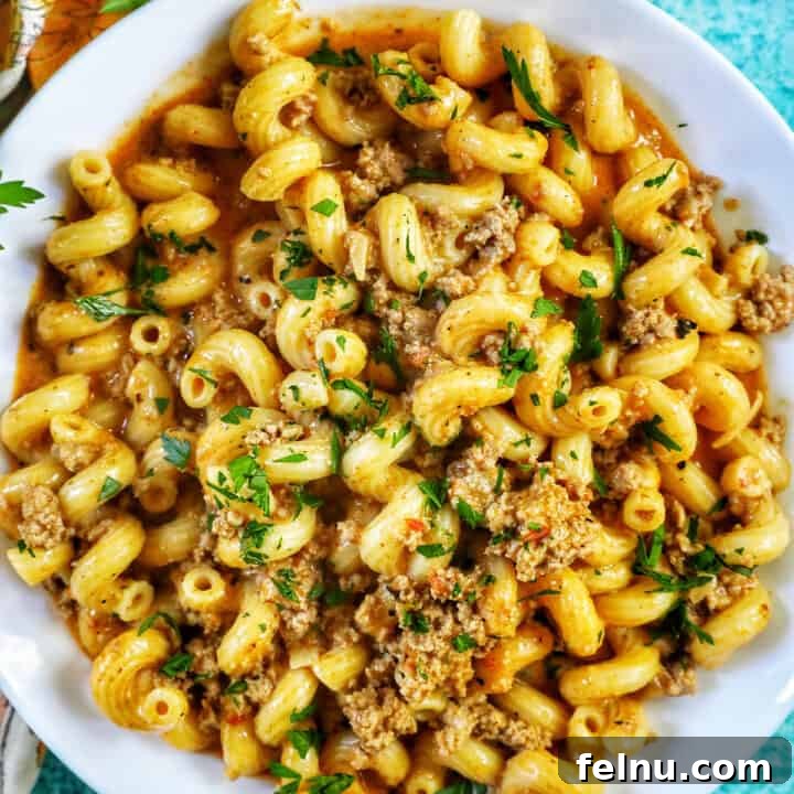 A bowl of dairy-free one-pot cheeseburger pasta with ground turkey and chopped parsley, ready to be served.