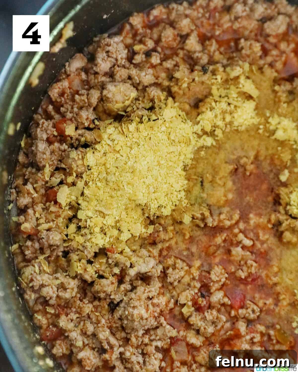 Creamy Dairy-Free Cheeseburger Mac Skillet 8 Nutritional yeast being added to the spiced ground meat, ready to be stirred in for a cheesy flavor boost.