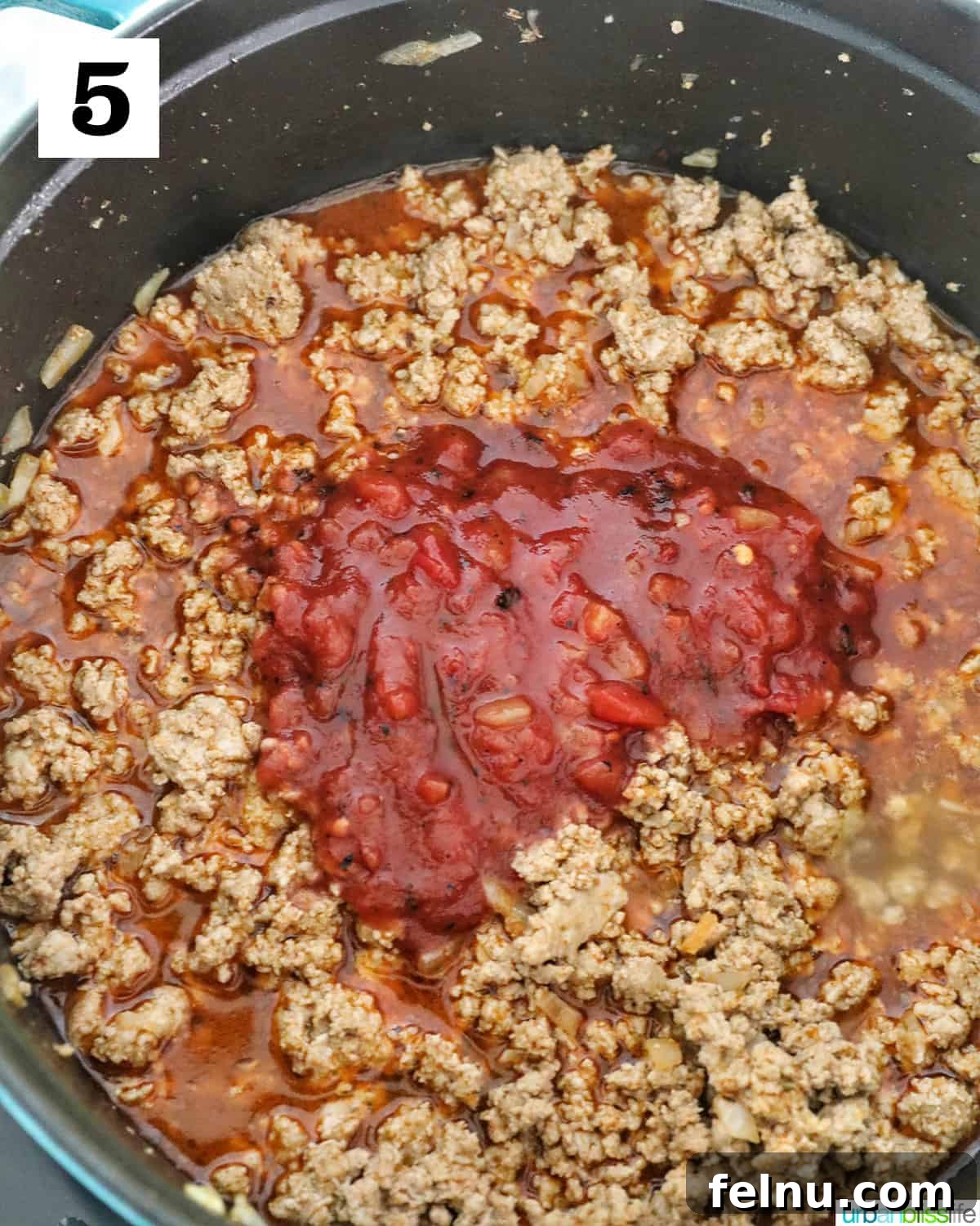 Creamy Dairy-Free Cheeseburger Mac Skillet 9 Canned fire-roasted diced tomatoes, with their juices, being added to the seasoned ground meat mixture in the Dutch oven.