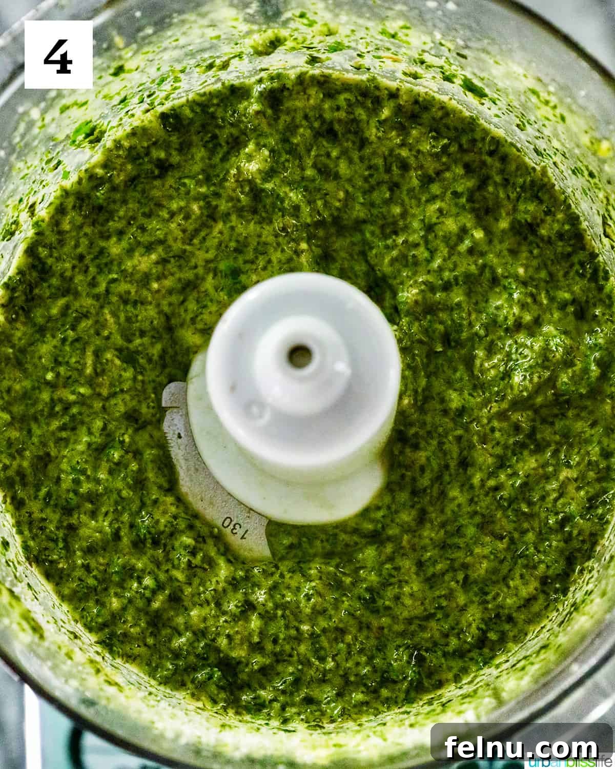 Zingy Mint Pesto 10 Bright green, fully blended mint pesto, smooth and vibrant, resting in the food processor bowl after all ingredients have been thoroughly processed.