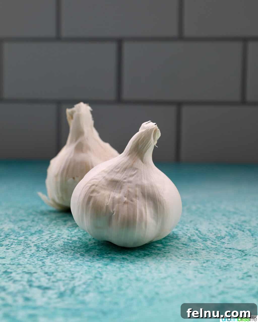 Building Your Essential Filipino Pantry 11 two garlic bulbs on a blue table with white tile background.