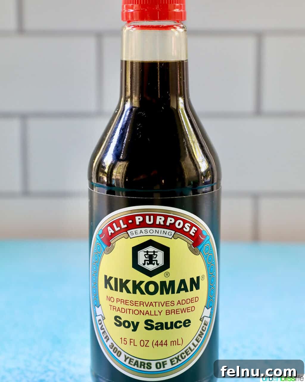 Building Your Essential Filipino Pantry 15 bottle of Kikkoman Soy Sauce on a blue table with white tile background.