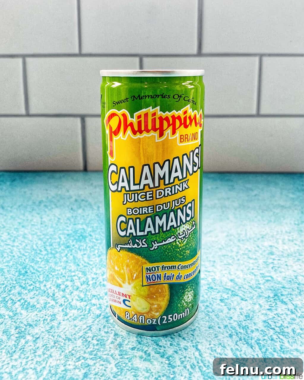 Building Your Essential Filipino Pantry 7 green and yellow can of calamansi juice on a bright blue table with kitchen tile background.