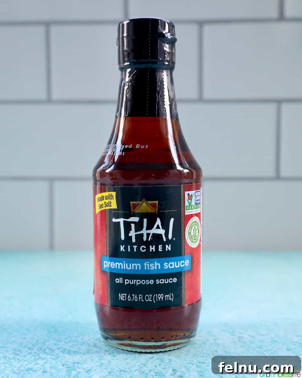 Building Your Essential Filipino Pantry 10 bottle of Thai kitchen fish sauce on a bright blue table with kitchen tile background.