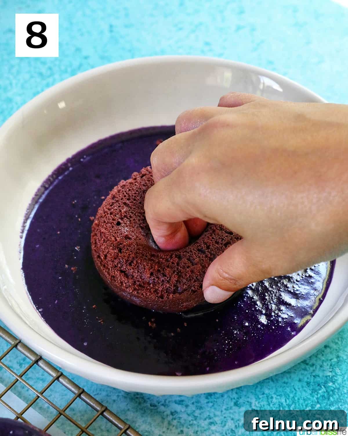 Ube Dream Donuts 16 Hand dipping a purple ube donut into a bowl of ube glaze.