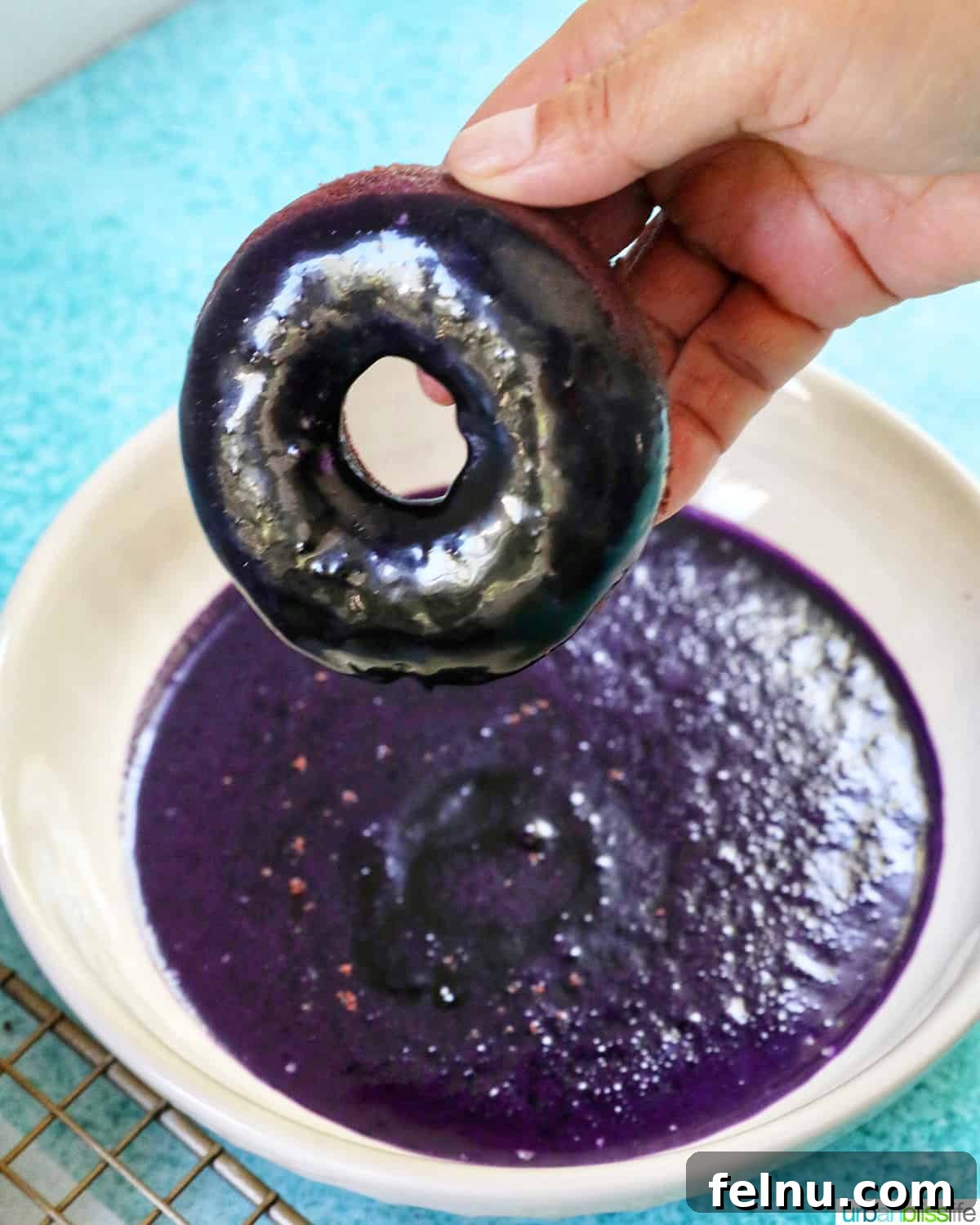 Ube Dream Donuts 19 Hand dipping purple ube donut into ube glaze.