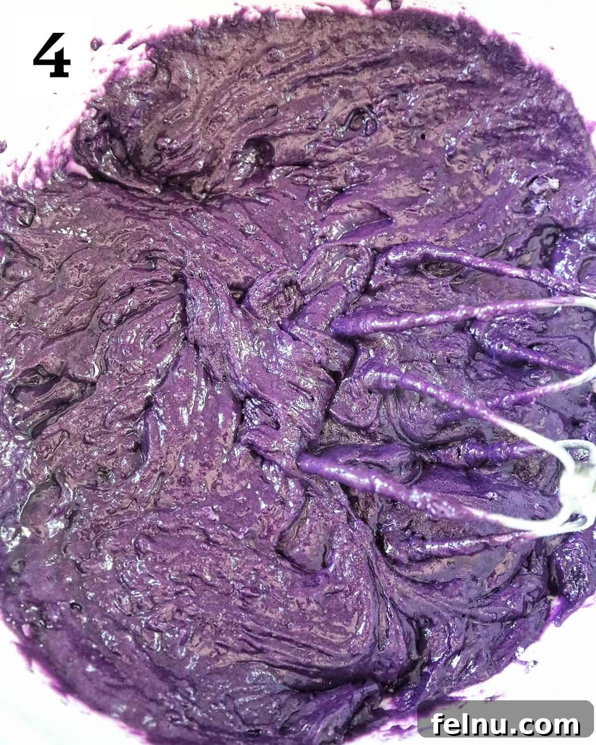 Ube Dream Donuts 10 Whisks in a bowl of purple ube donut batter.