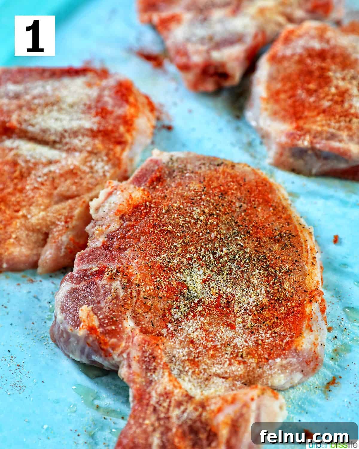 Instant Pot Pork Chop Rice Bowl 5 Close-up of well-seasoned pork chops on parchment paper, placed on a bright blue table.