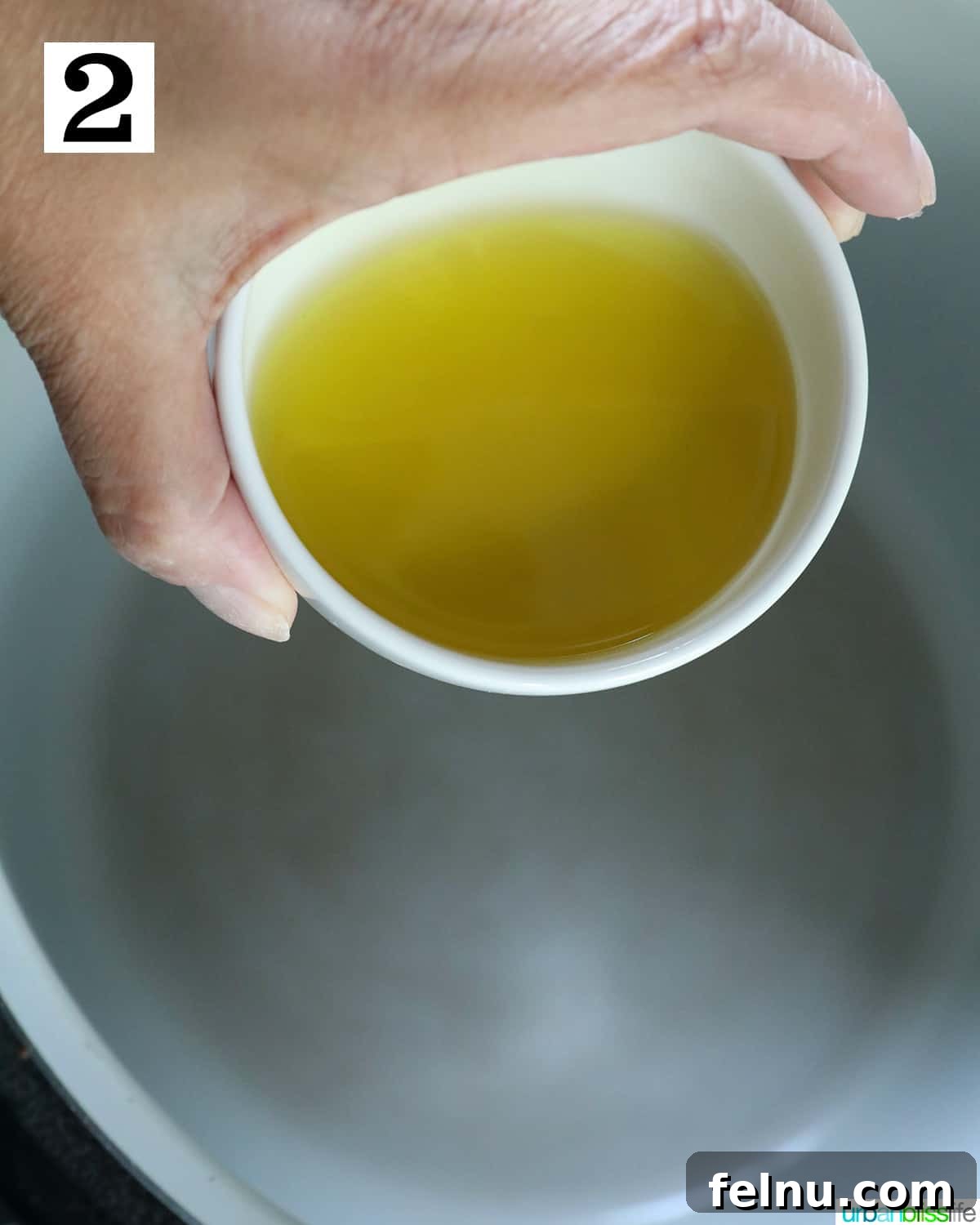Instant Pot Pork Chop Rice Bowl 6 A hand pouring olive oil into the inner pot of a Ninja Foodi or Instant Pot.