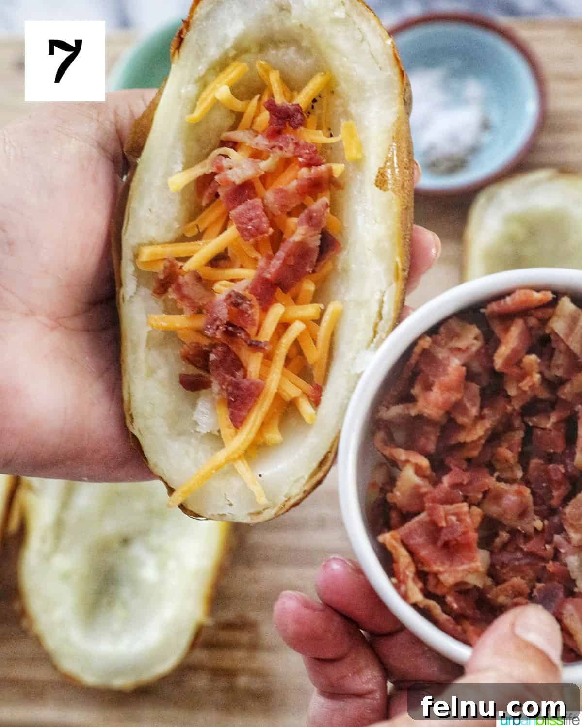 Ultimate Air Fryer Potato Skins 11 hand holding a bowl of bacon on the right and a hand holding a potato skin half topped with cheddar cheese and bacon on the left.