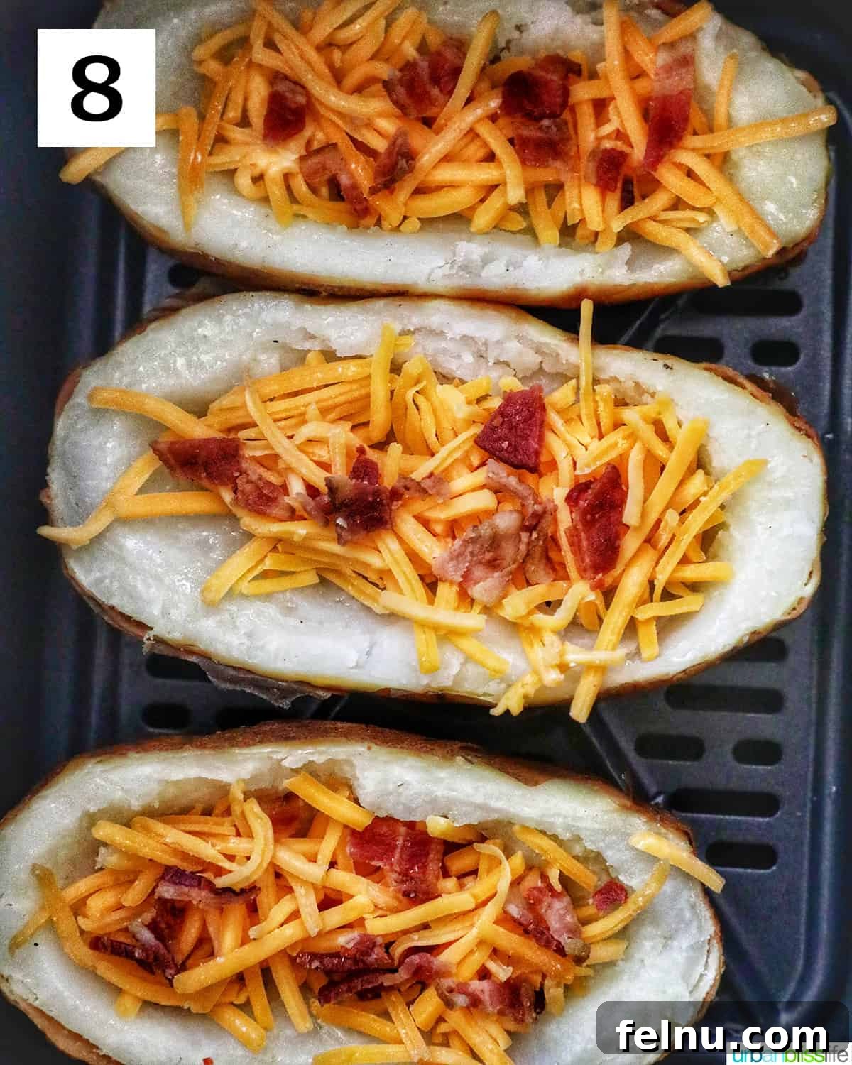 Ultimate Air Fryer Potato Skins 12 three potato skins topped with cheddar cheese and bacon in an air fryer basket.
