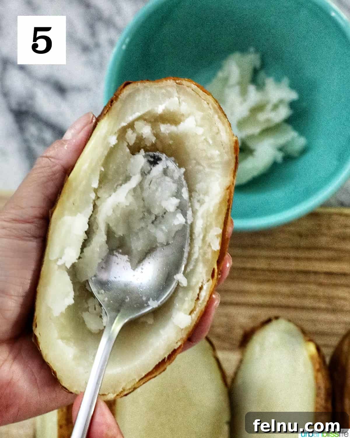 Ultimate Air Fryer Potato Skins 9 a spoon scooping out the center of a baked potato.