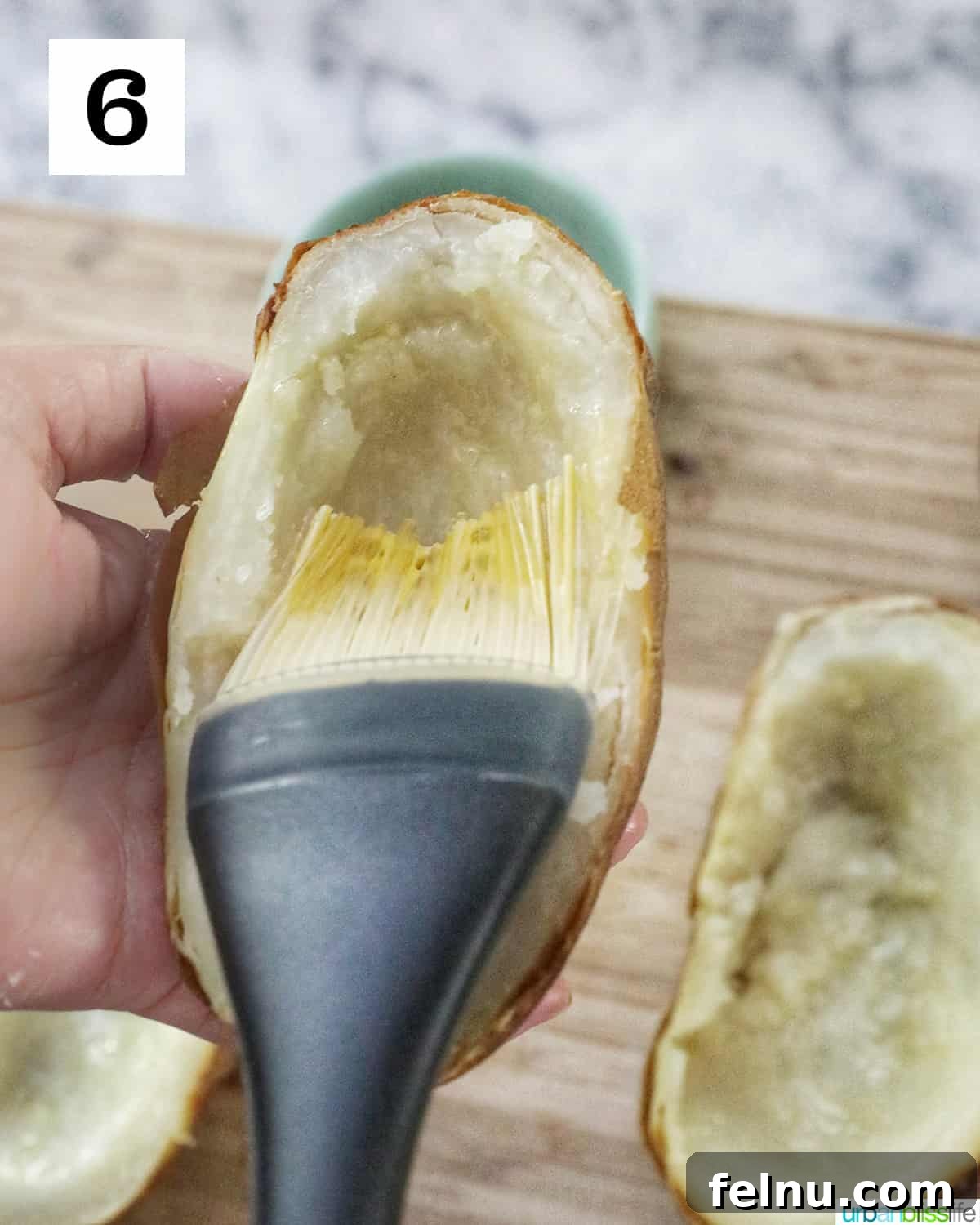 Ultimate Air Fryer Potato Skins 10 a pastry brush brushing a hollowed out potato half with olive oil.