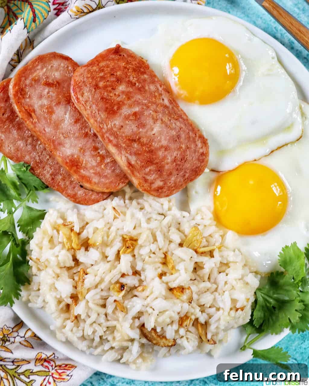 Spamsilog A Filipino Breakfast Classic 2 Plate of Spamsilog: slices of Spam, two eggs over easy, and Filipino Sinangag garlic rice with greens.
