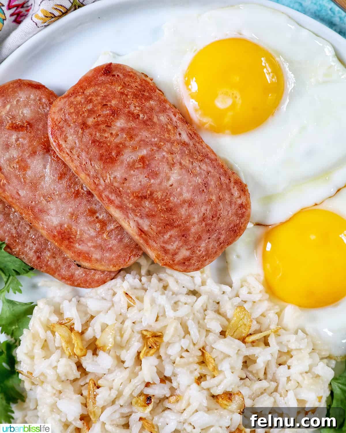 Spamsilog A Filipino Breakfast Classic 8 Plate of Spamsilog: slices of Spam, two eggs over easy, and Filipino Sinangag garlic rice with greens.