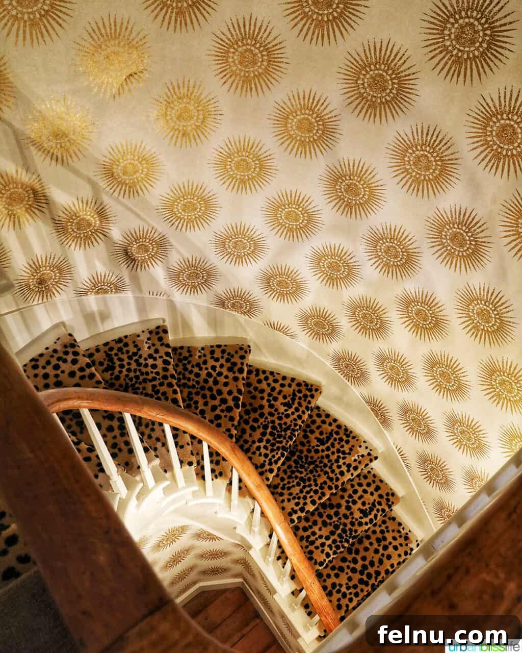 A dramatic staircase within Kubli Haus, showcasing gold and cream wallpaper alongside animal print stair carpeting.