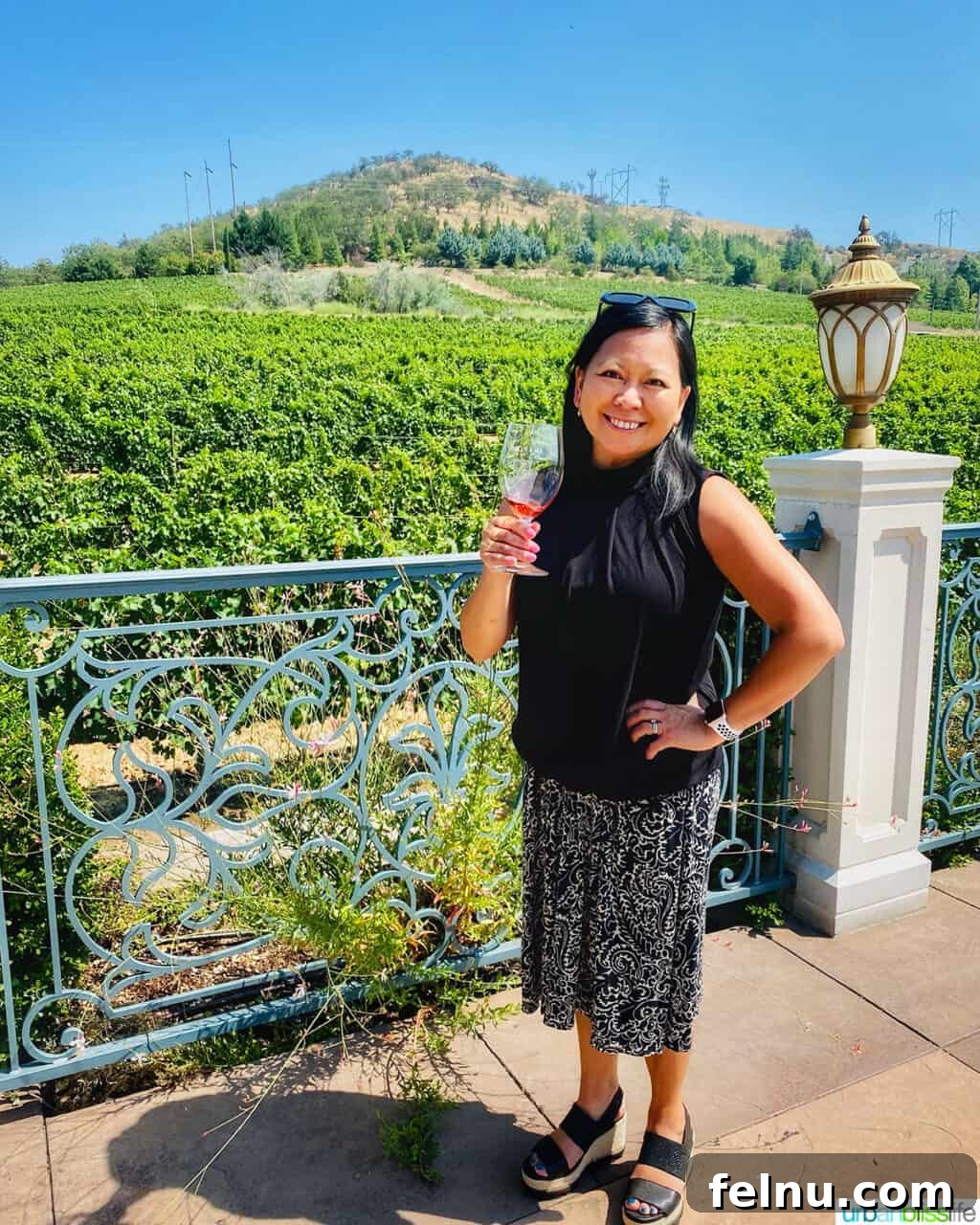 Belle Fiore Vineyard 13 Marlynn Schotland holding a glass of rosé wine in front of Belle Fiore Winery vineyards