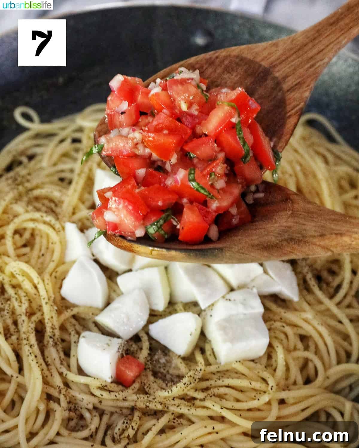 Adding tomatoes and mozzarella to spaghetti.