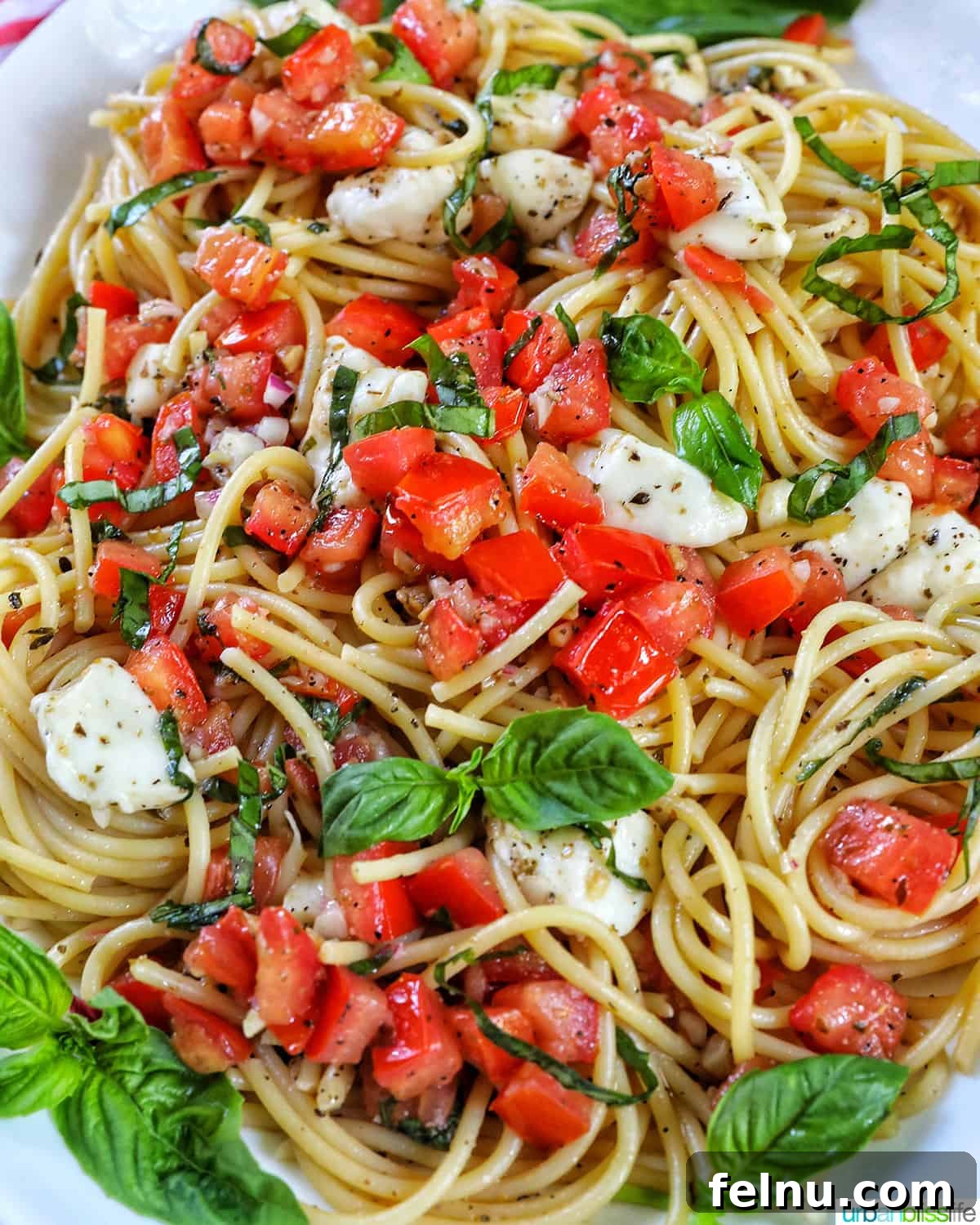Bruschetta pasta with tomatoes, basil, and mozzarella cheese in a big serving bowl.
