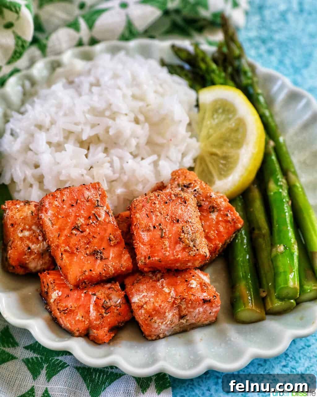 Golden Crispy Salmon Bites 3 air fryer salmon bites with white rice, asparagus, and lemon slice.
