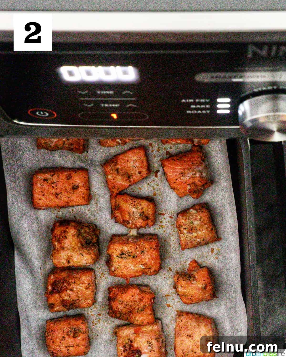 Golden Crispy Salmon Bites 6 air fryer salmon bites cooked on parchment paper in an air fryer.