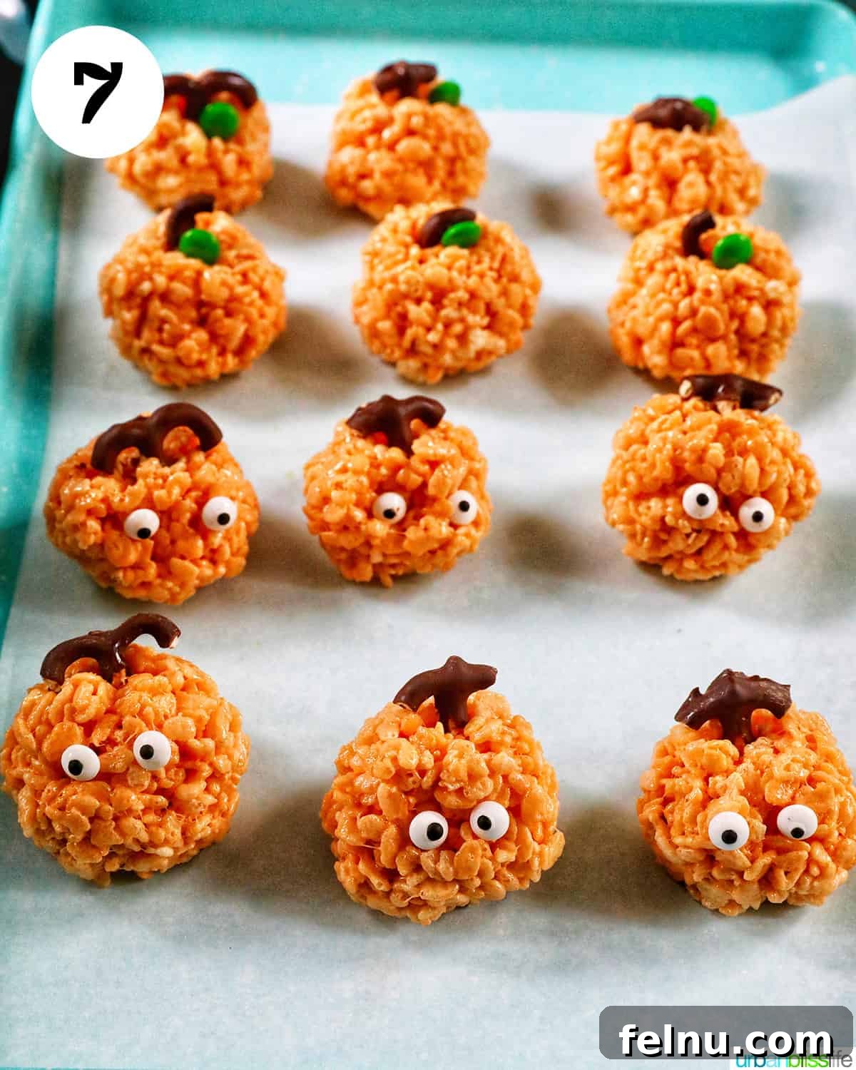 Seasonal Pumpkin Crunch Squares 15 Decorated pumpkin rice krispie treats setting on a baking sheet lined with parchment paper.