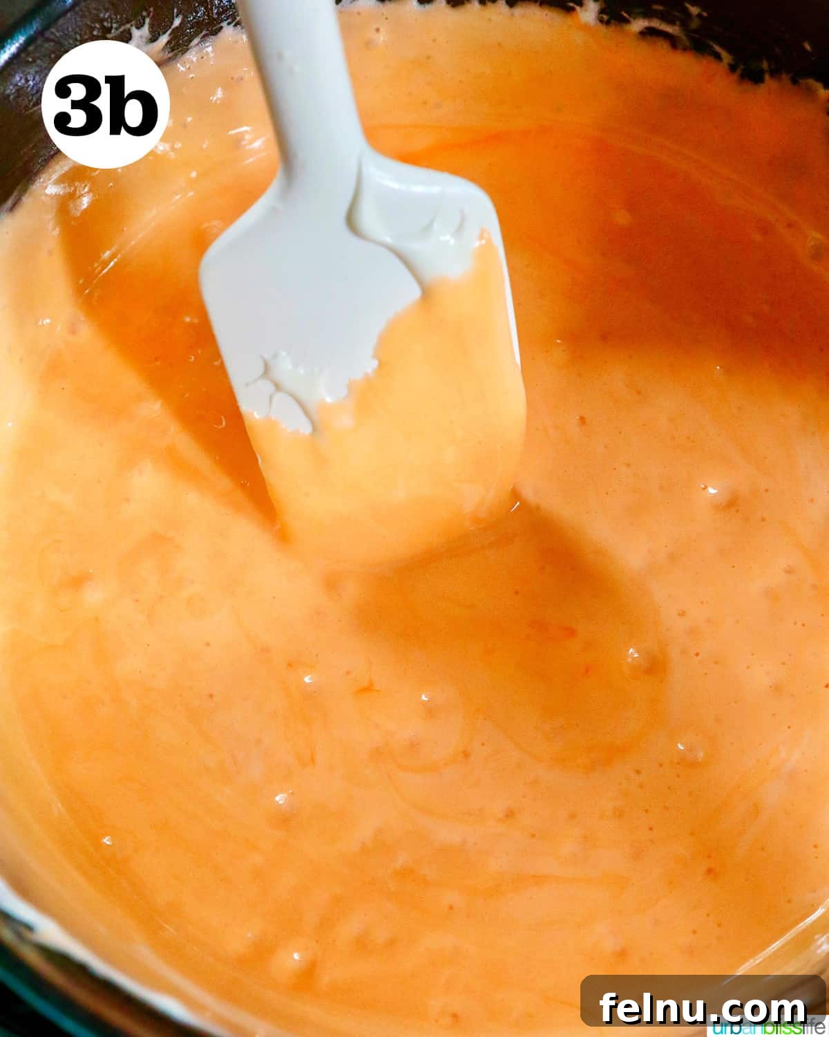 Seasonal Pumpkin Crunch Squares 8 A heatproof spatula stirring brightly colored orange melted marshmallows.