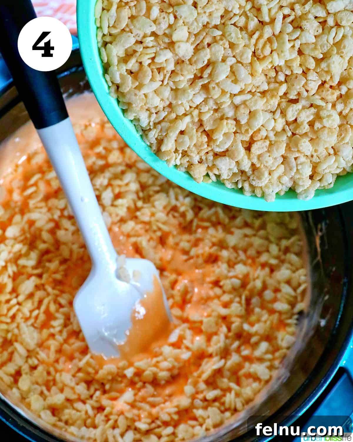 Seasonal Pumpkin Crunch Squares 9 Rice Krispies cereal being poured into the melted orange marshmallow mixture.