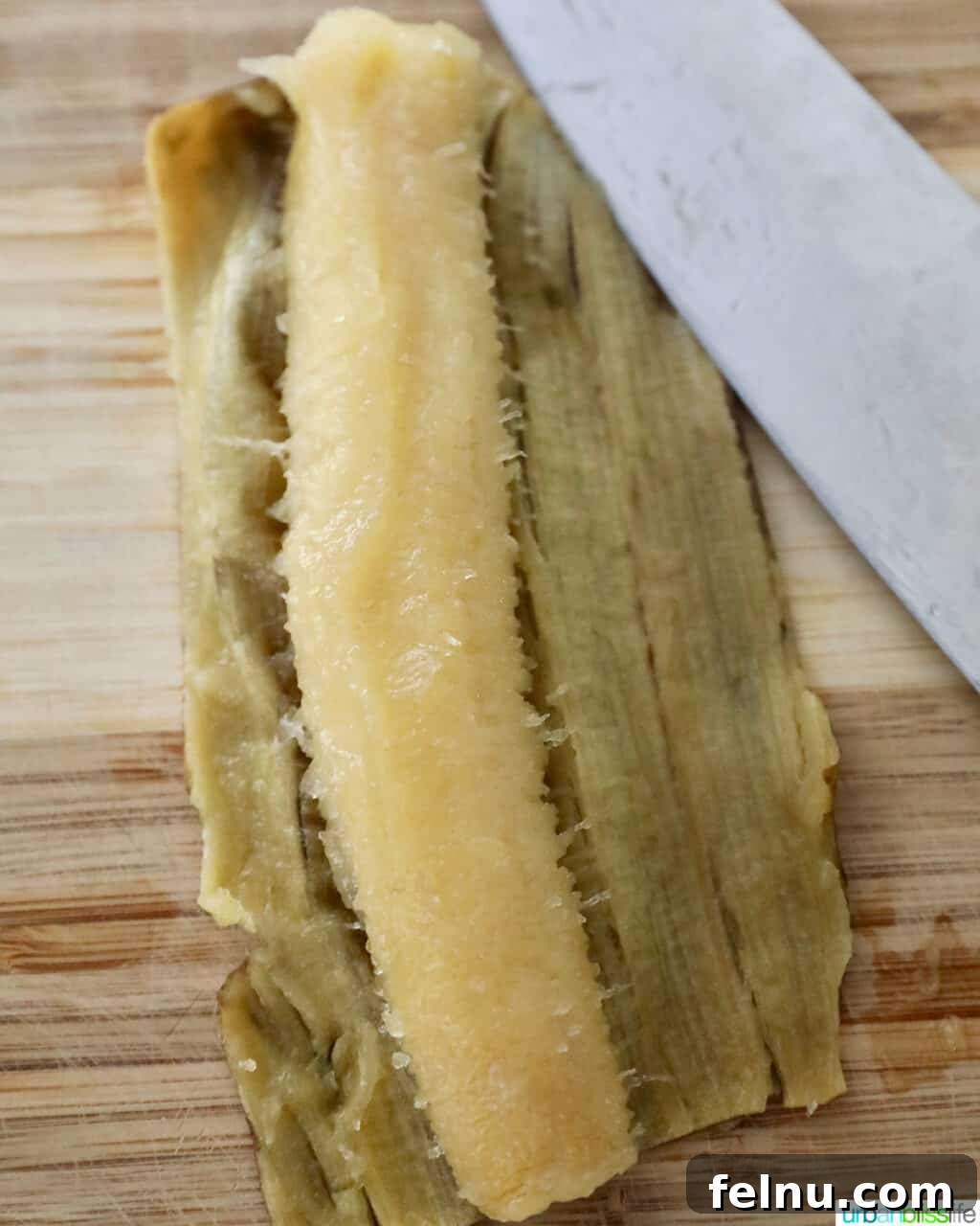 Creative Banana Bakes: Turning Overripe into Delicious 4 A peeled ripe banana on a cutting board with a knife, ready to be sliced or mashed.