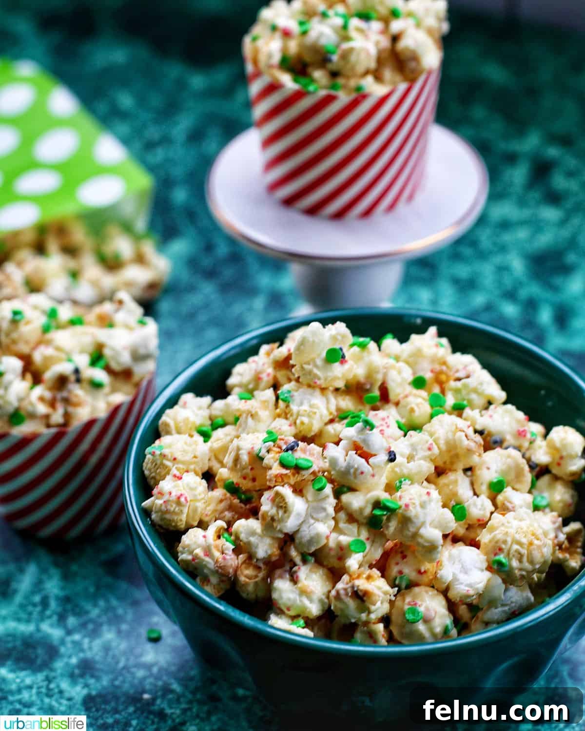 Festive Holiday Popcorn Mix 2 Christmas popcorn in bags and popcorn holders on a green table.