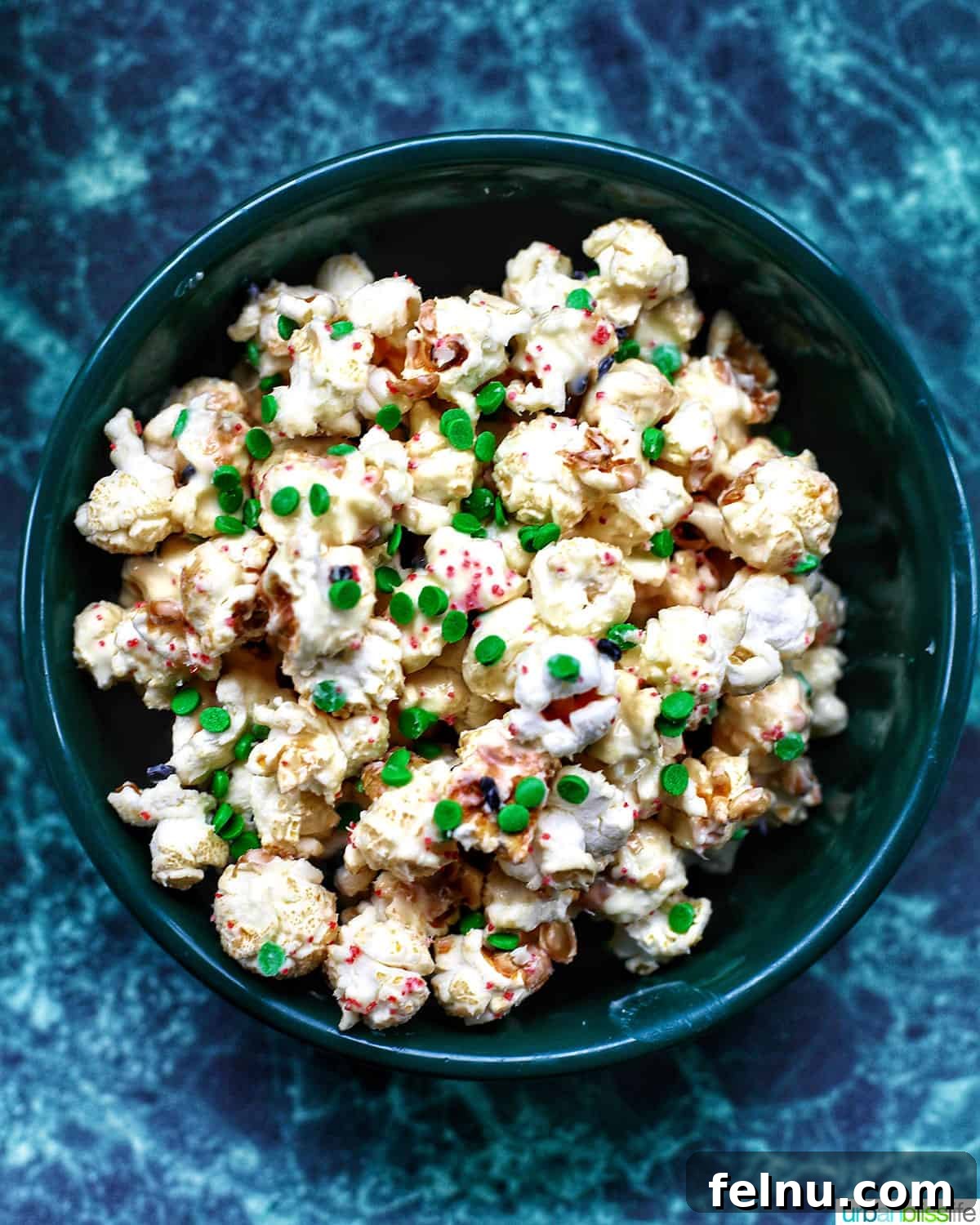 Festive Holiday Popcorn Mix 3 big bowl of Christmas popcorn on a green table.