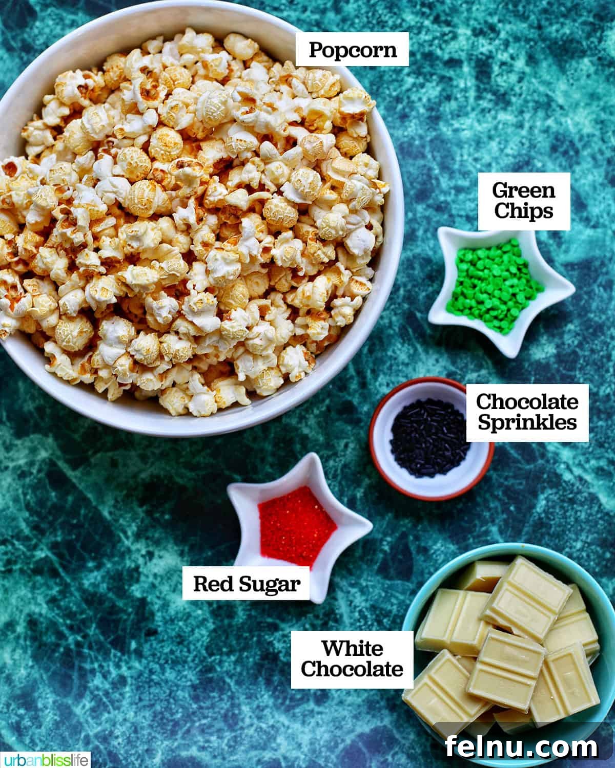 Festive Holiday Popcorn Mix 4 bowls of ingredients to make Christmas popcorn on a green table.
