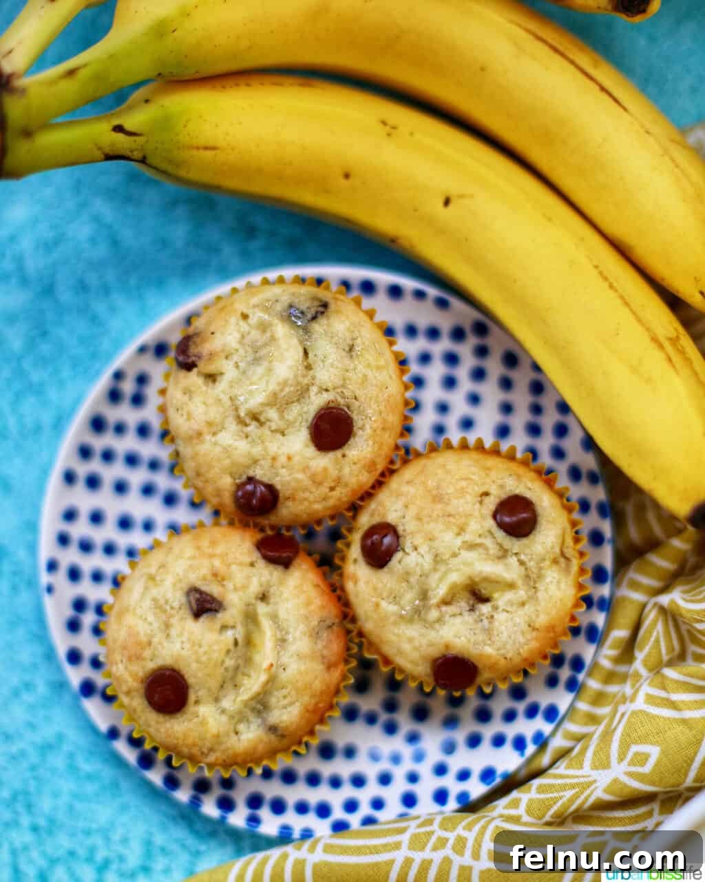 Banana Chocolate Chunk Muffins 12 Three banana chocolate chip muffins on a polka dot plate with two bananas.