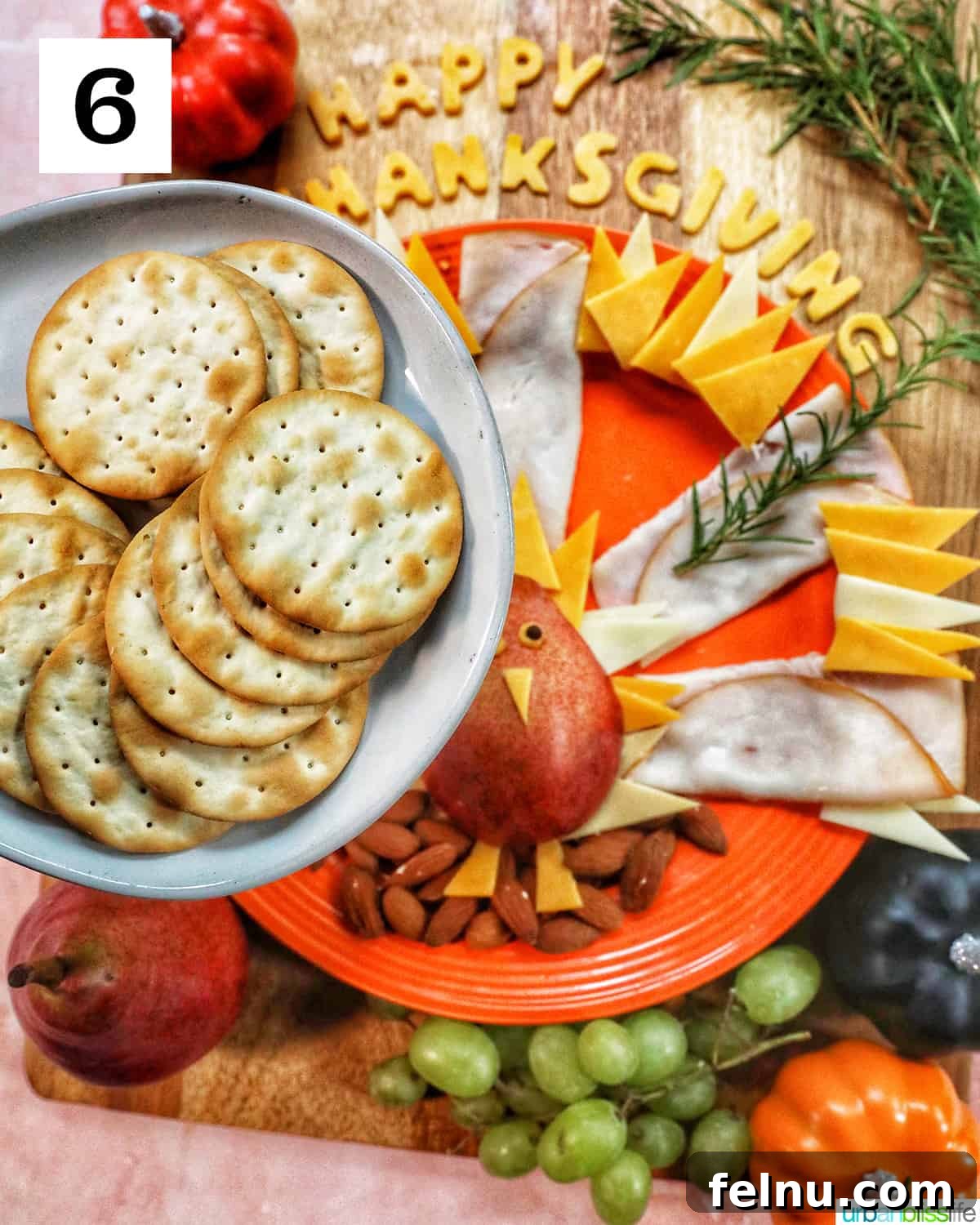 plate of crackers over a thanksgiving charcuterie board with meat, cheese, fruit.