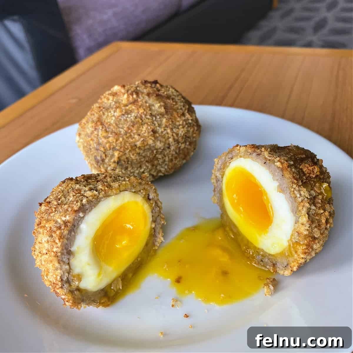 Perfectly soft-boiled Scotch Eggs with a golden-brown sausage casing.