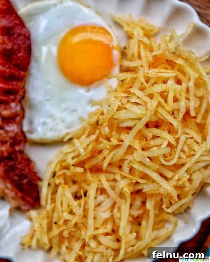 Perfectly shredded air fryer hash browns served on a white plate.